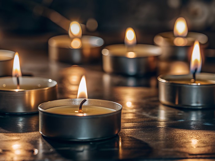 Multiple tea lights glowing on a table in a dimly lit room.